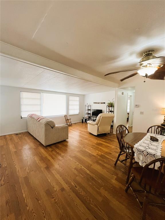 A living and dining area features hardwood floors, a beige sofa, and a ceiling fan — 6916 MARLIN LANE, BRADENTON, FL
