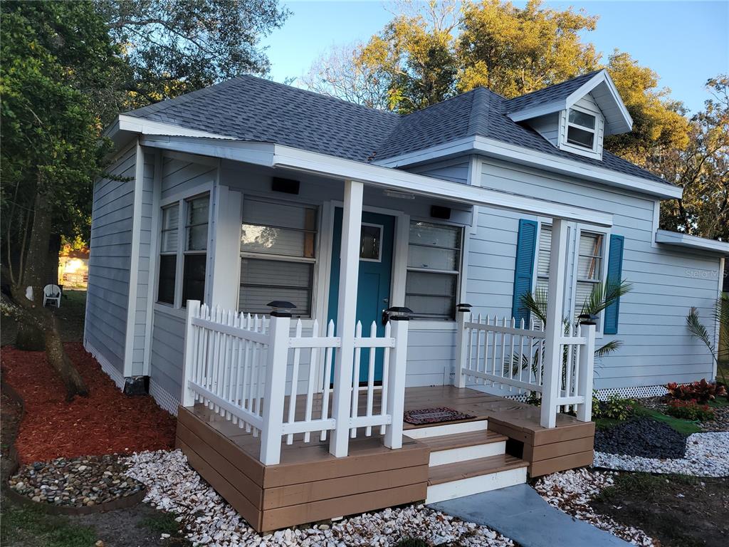 A light blue cottage with a white picket fence, front porch, and a dormer window — 5548 11TH STREET, ZEPHYRHILLS, FL