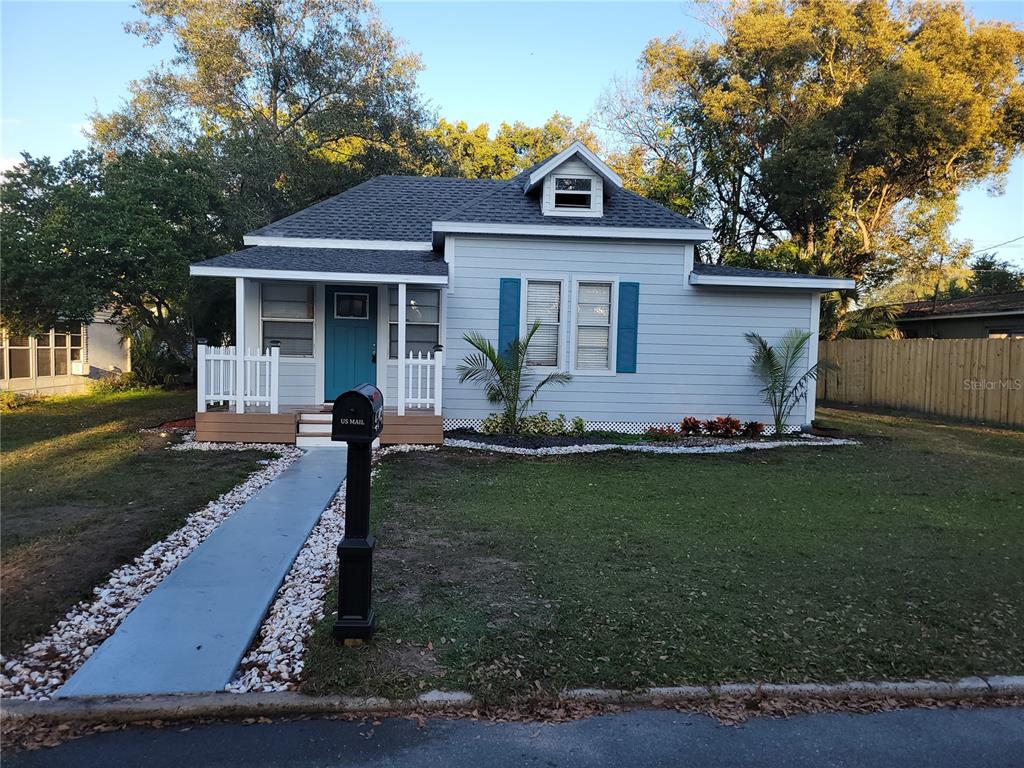 A light blue, single-story house with a front porch, dark shutters, and a small dormer — 5548 11TH STREET, ZEPHYRHILLS, FL