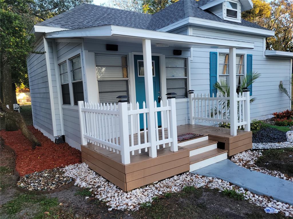 A light blue house features a small wooden front porch with a white picket fence — 5548 11TH STREET, ZEPHYRHILLS, FL