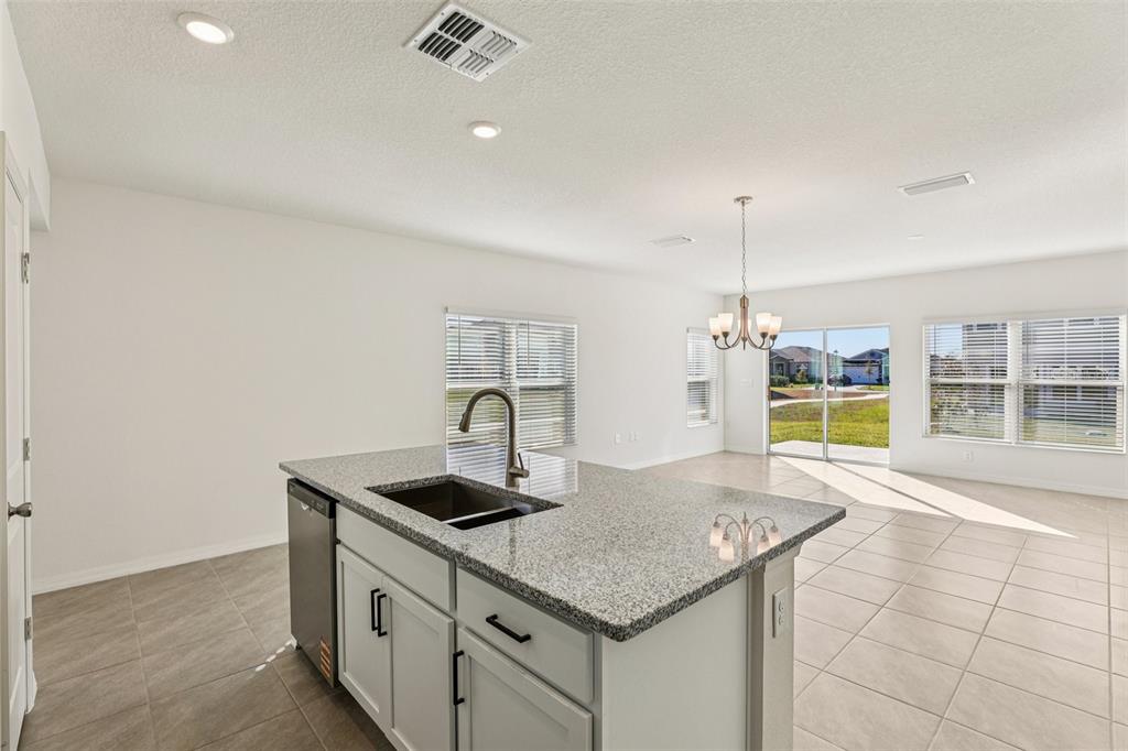 A kitchen island with a granite countertop and sink sits in a bright, tiled room — 387 SEQUOIA DRIVE, LAKE WALES, FL