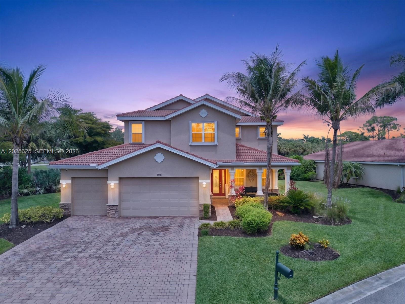 A two-story suburban house with a paved driveway, tile roof, and palm trees at dusk — NORTH FORT MYERS, FL