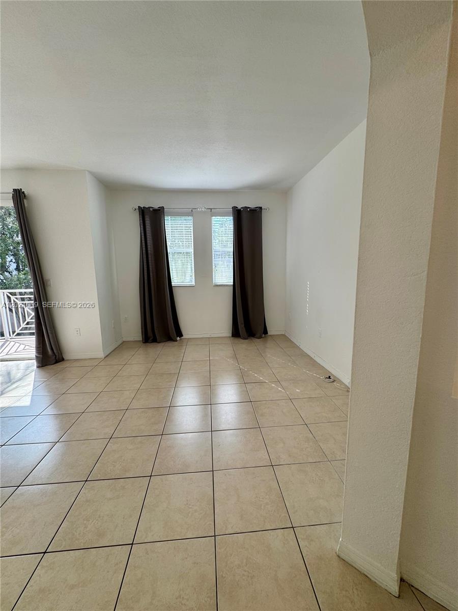 An empty room features beige tile flooring, white walls, and two windows with dark curtains — 8936 W Flagler St # 201, Miami FL 33174, MIAMI, FL