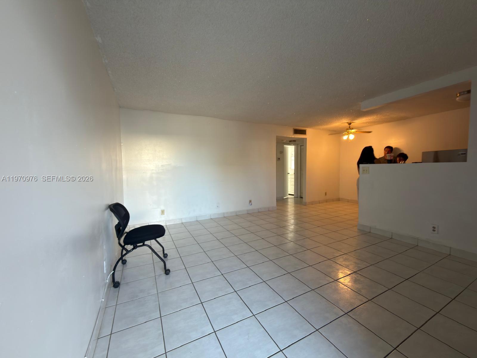 An empty room with white walls, tiled flooring, and a partial wall separating the kitchen — 30 SE 4th Ave # 103, Hallandale Beach FL 33009, HALLANDALE BEACH, FL