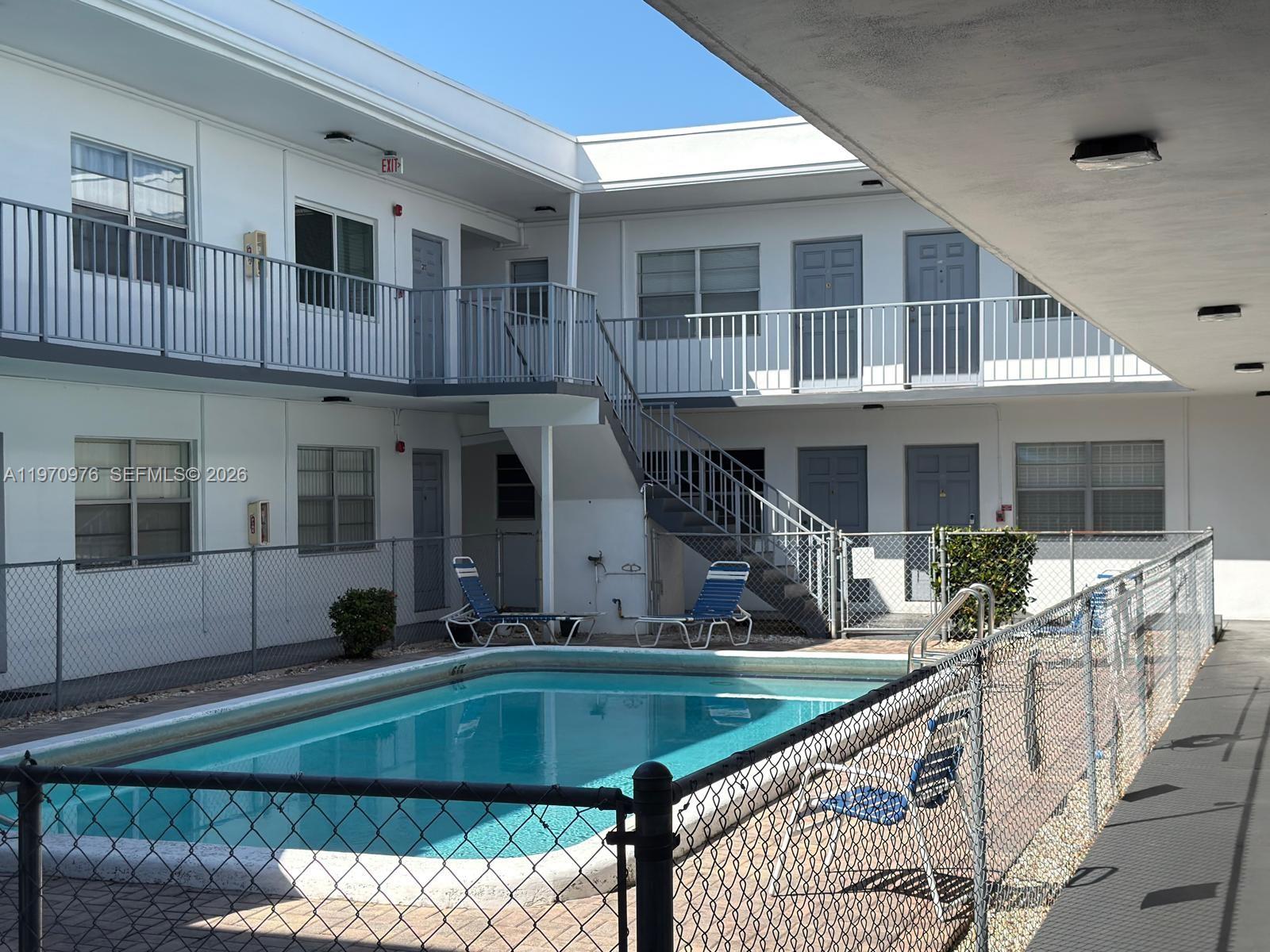 An outdoor swimming pool sits in the courtyard of a two-story apartment building — 30 SE 4th Ave # 103, Hallandale Beach FL 33009, HALLANDALE BEACH, FL