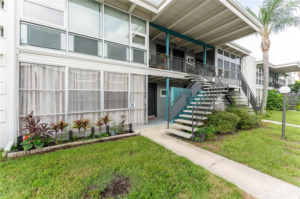A two-story apartment building features a metal staircase leading to an upper-level balcony — 151 N ORLANDO AVENUE UNIT #115, WINTER PARK, FL