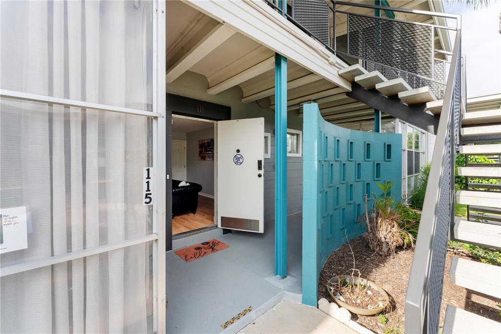 An exterior view of an apartment entrance with a teal decorative breeze block wall — 151 N ORLANDO AVENUE UNIT #115, WINTER PARK, FL