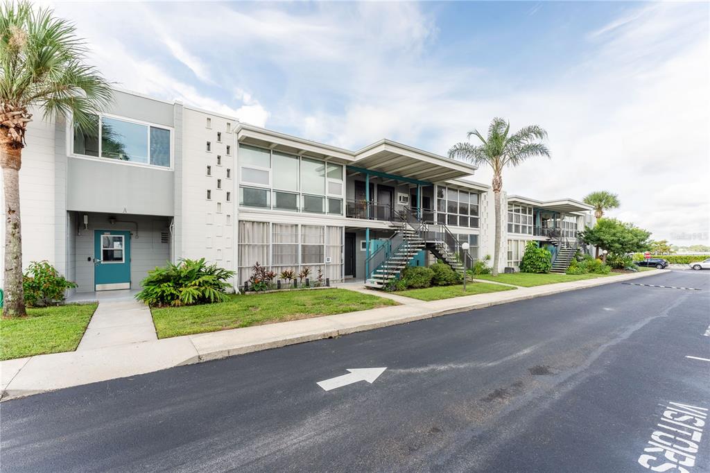 A two-story apartment building with a teal door, exterior staircases, and palm trees — 151 N ORLANDO AVENUE UNIT #115, WINTER PARK, FL