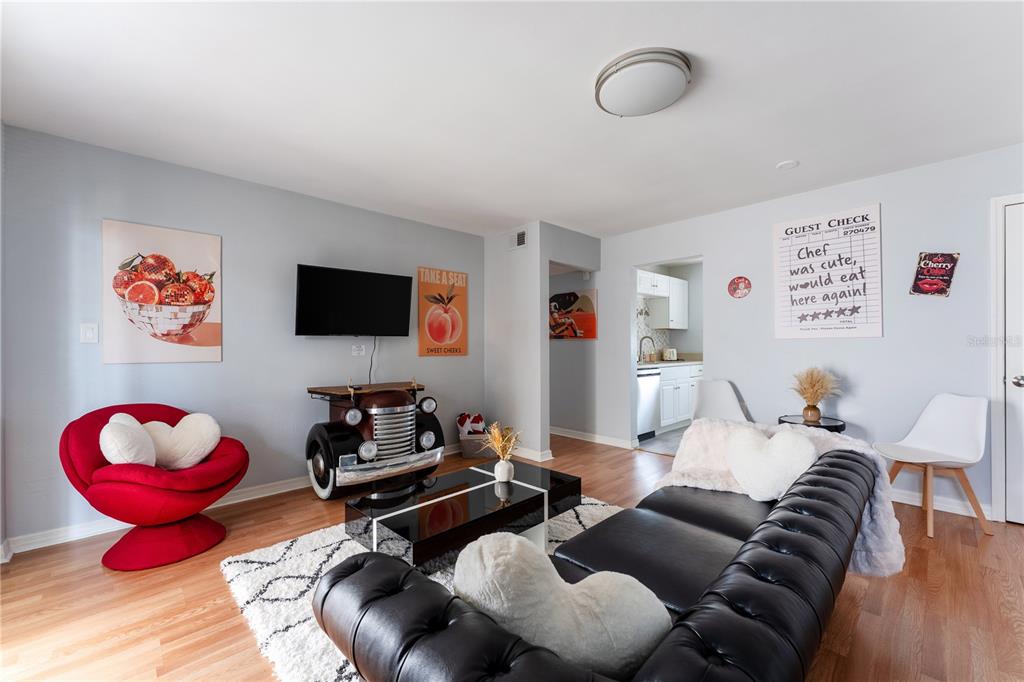 A living room features a black leather sofa, a red accent chair, and a truck-themed console — 151 N ORLANDO AVENUE UNIT #115, WINTER PARK, FL