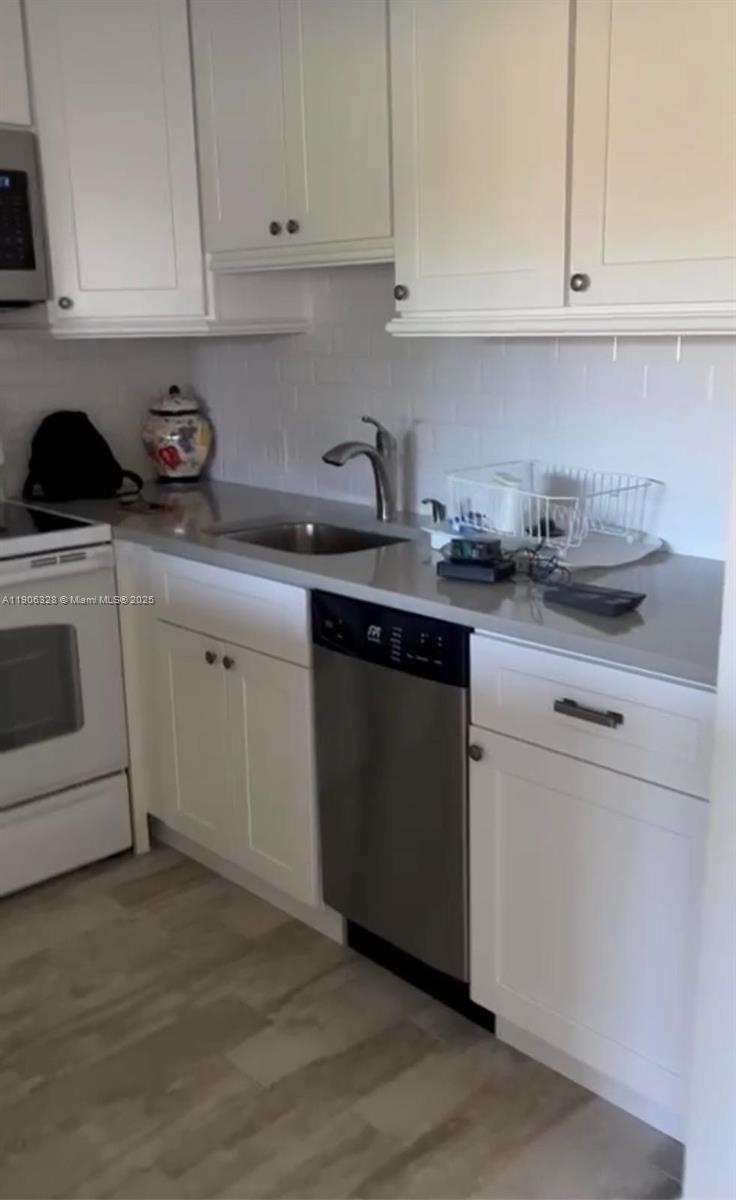 A kitchen features white cabinets, a stainless steel dishwasher, and a gray countertop — 22 Brighton A # 22, Boca Raton FL 33434, BOCA RATON, FL