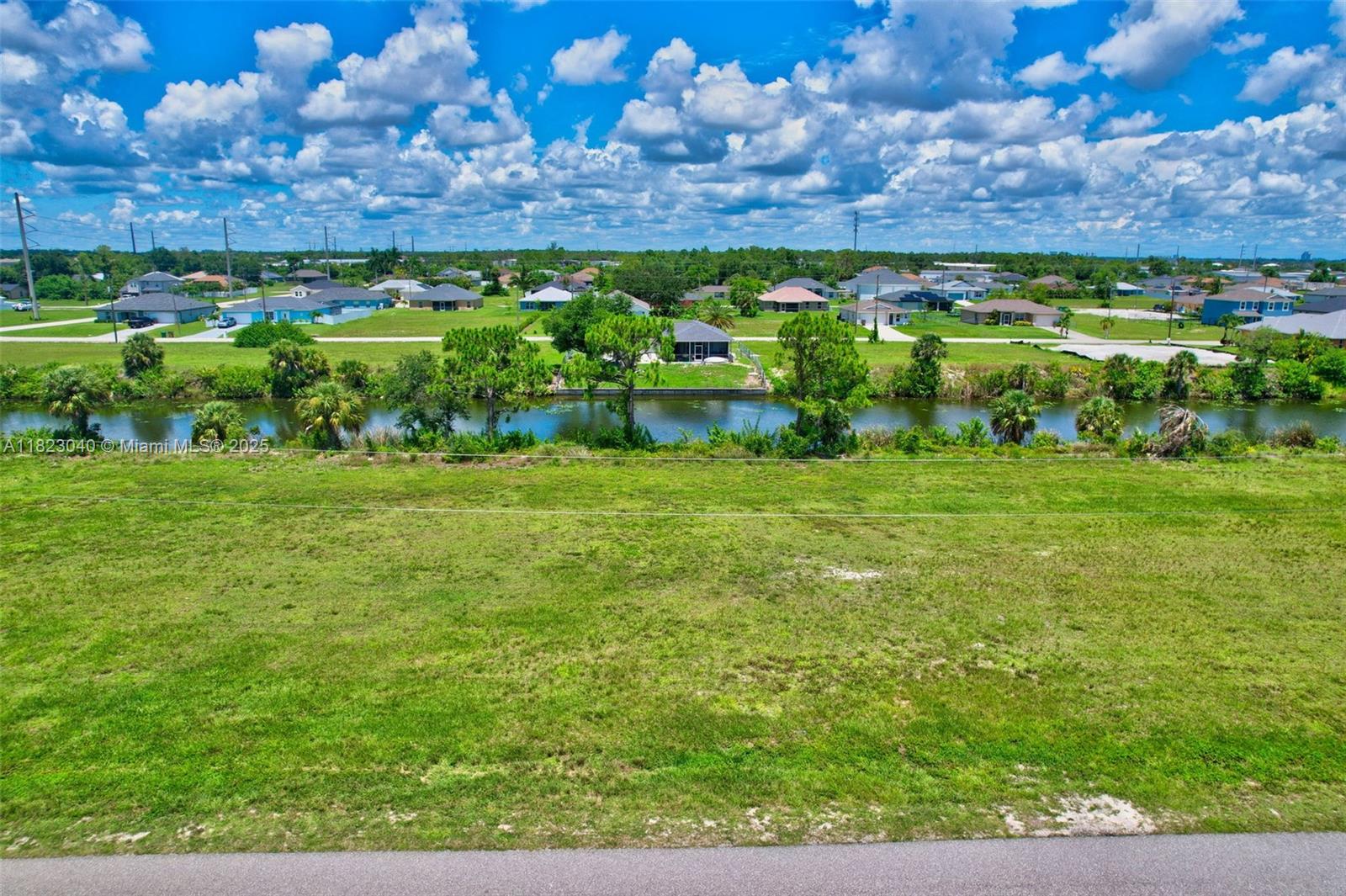 An elevated view shows a grassy lot overlooking a canal with houses in the background — 2625 NE 5th PL, Cape Coral FL 33909, CAPE CORAL, FL