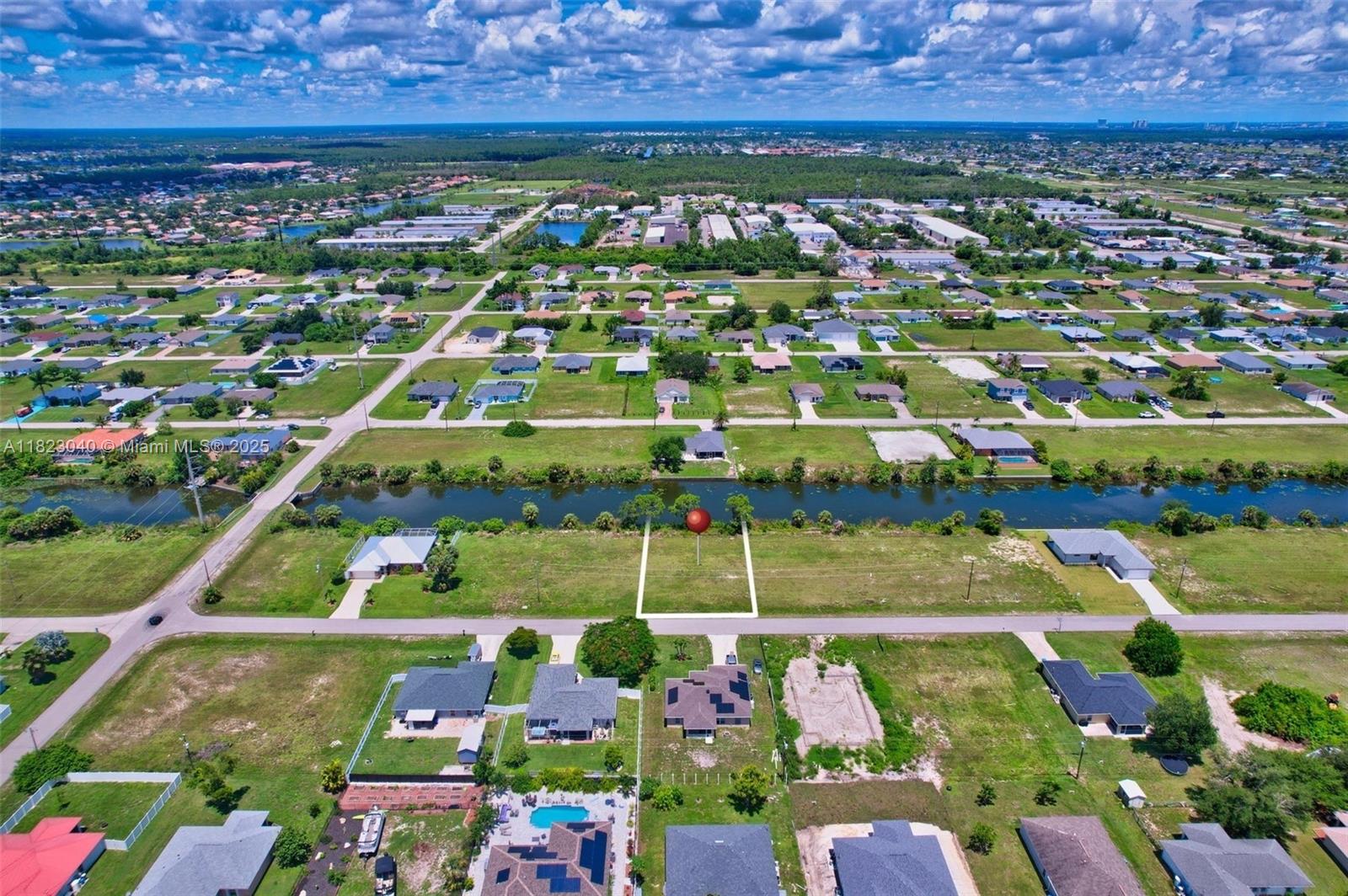 An aerial view shows a vacant residential lot outlined in white next to a canal — 2625 NE 5th PL, Cape Coral FL 33909, CAPE CORAL, FL