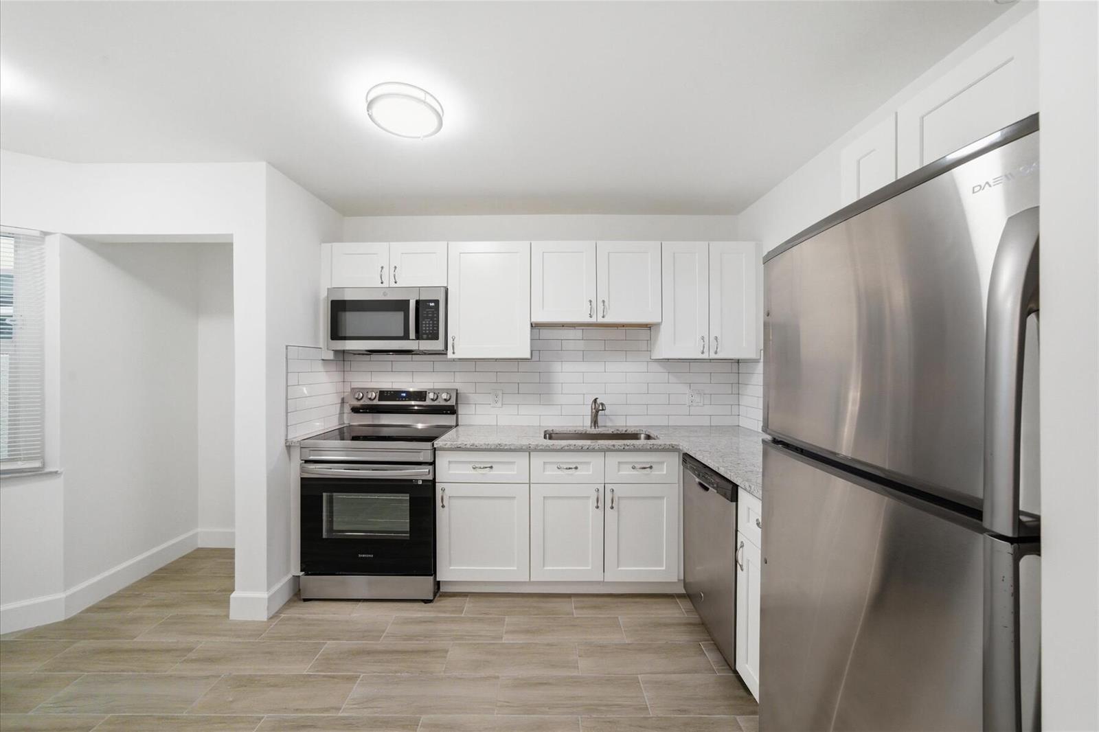 A kitchen with white cabinets, stainless steel appliances, granite countertops, and light wood-look flooring — 428 Grove Isle Circle # 9, Vero Beach FL 32962, VERO BEACH, FL