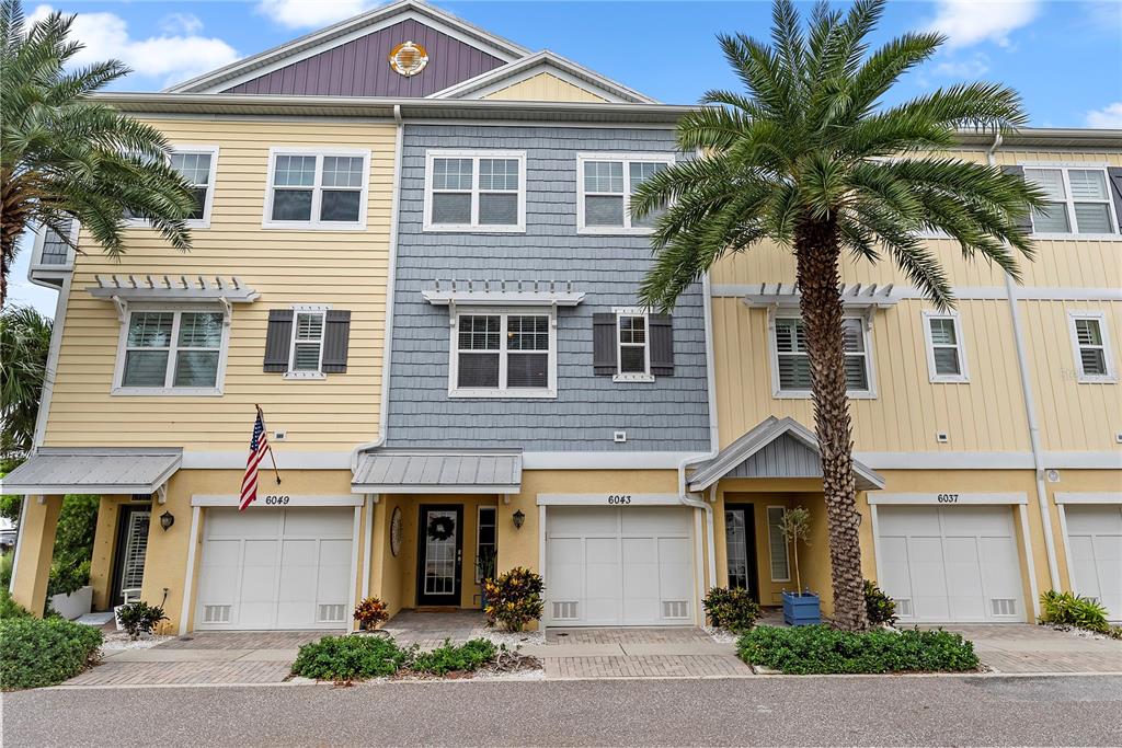 A row of three-story townhomes with yellow and gray siding and attached garages — 6043 ANCHORAGE WAY S, ST PETERSBURG, FL