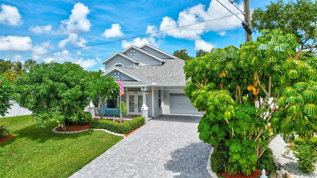A waterfront house with a boat lift, screened pool enclosure, and wooden dock at dusk — 360 46TH COURT E, BRADENTON, FL