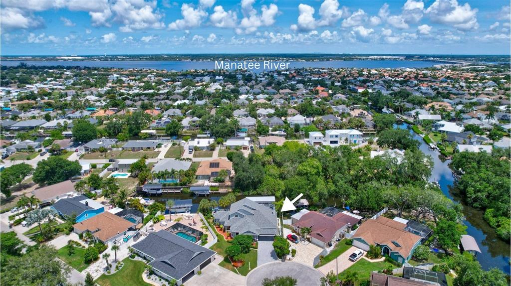 An aerial view shows a suburban neighborhood with houses along a canal near the Manatee River — 360 46TH COURT E, BRADENTON, FL