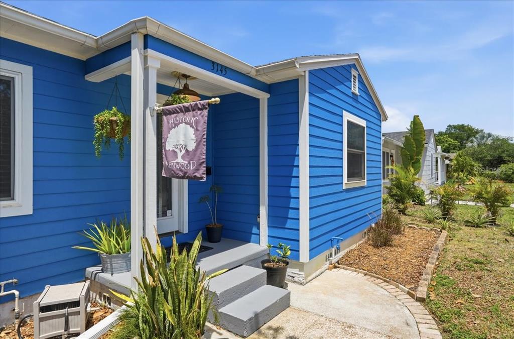 A blue house with white trim features a front porch and a small garden — 3145 8TH AVENUE N, ST PETERSBURG, FL