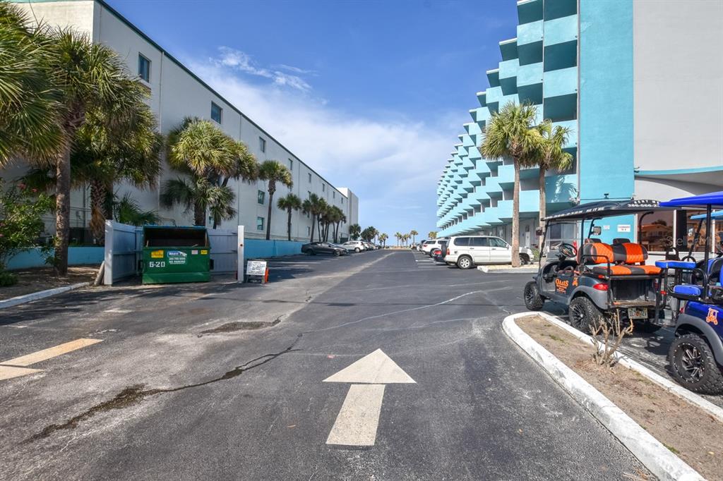 A paved parking lot sits between two multi-story buildings with palm trees and golf carts — 313 S ATLANTIC AVENUE UNIT 2170, DAYTONA BEACH, FL