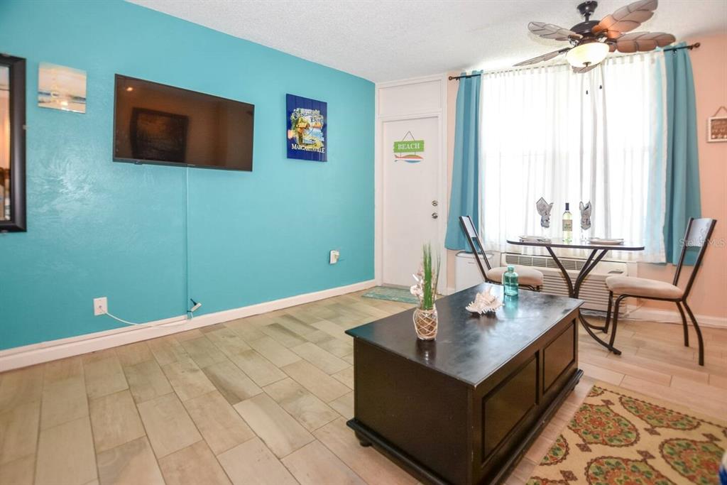 A living room features a bright blue accent wall, a television, and a small dining area — 313 S ATLANTIC AVENUE UNIT 2170, DAYTONA BEACH, FL