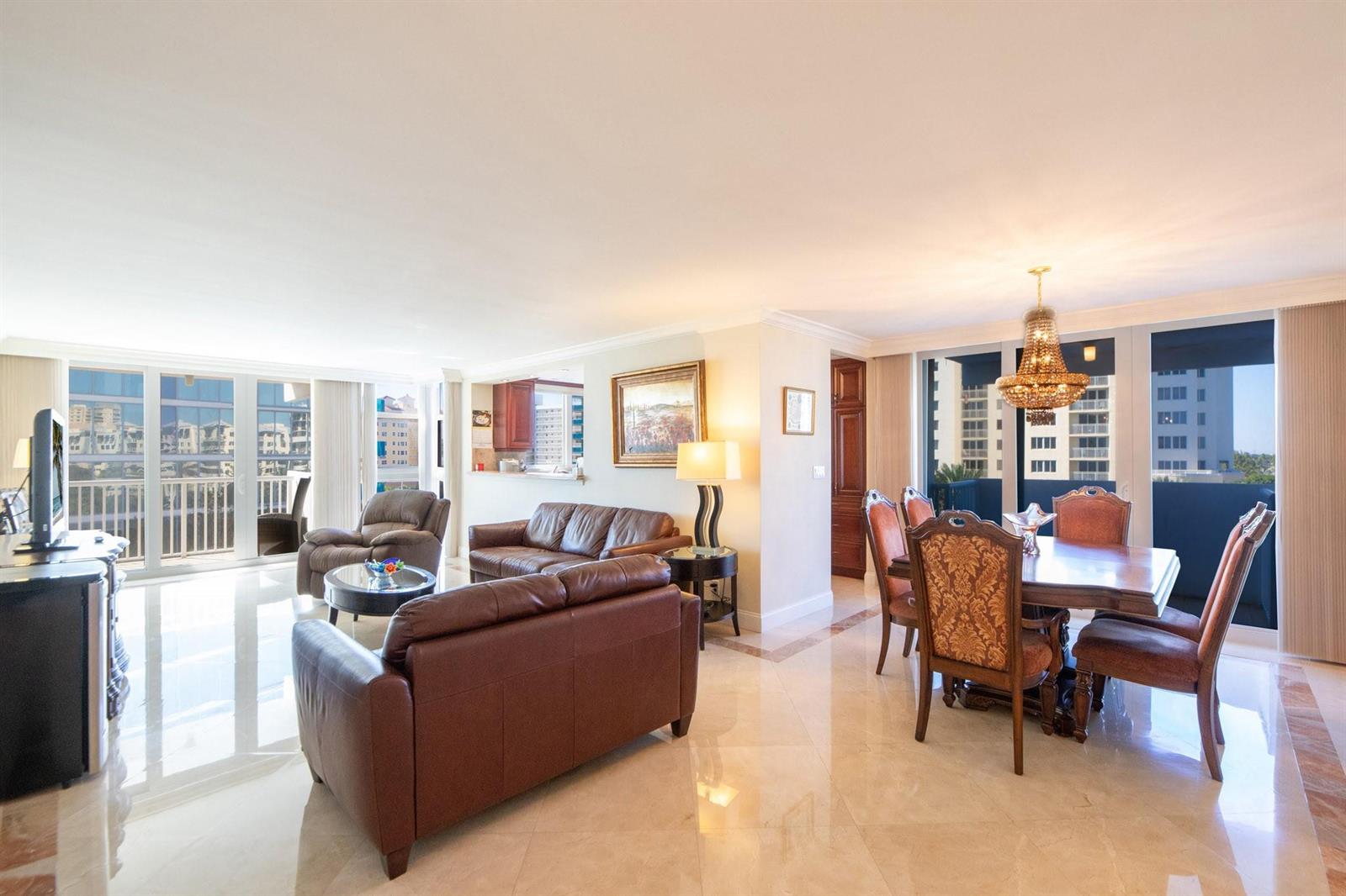 A living and dining area with leather furniture, a crystal chandelier, and floor-to-ceiling windows — 1370 S Ocean Boulevard # 604, Pompano Beach FL 33062, POMPANO BEACH, FL