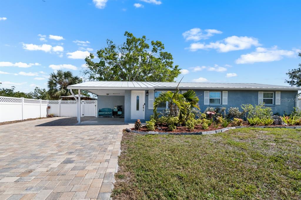 A single-story house with a metal roof, a paved driveway, and a carport — 107 6TH STREET NW, RUSKIN, FL