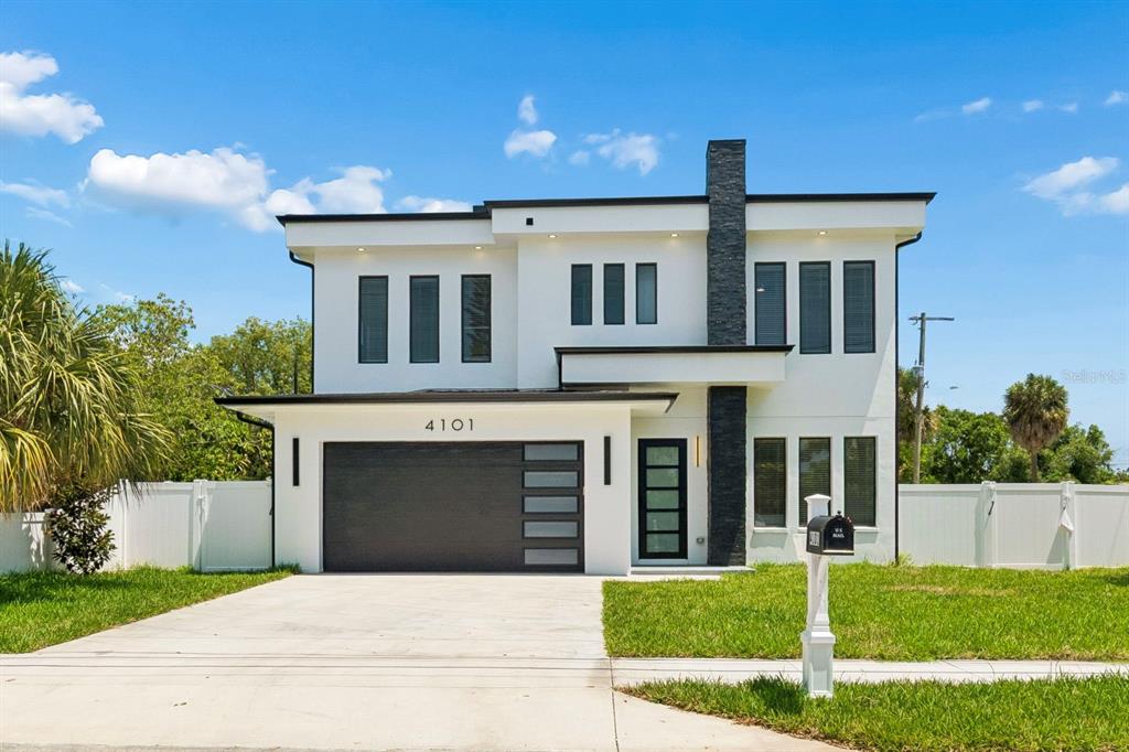 A modern two-story house with white stucco, a dark stone chimney, and a garage — 4101 W MANGO AVENUE, TAMPA, FL