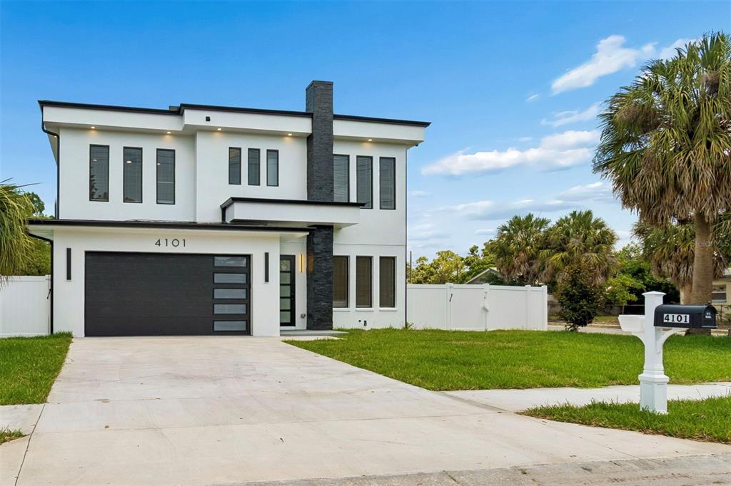 A modern two-story house with white stucco walls, a black garage door, and stone accents — 4101 W MANGO AVENUE, TAMPA, FL