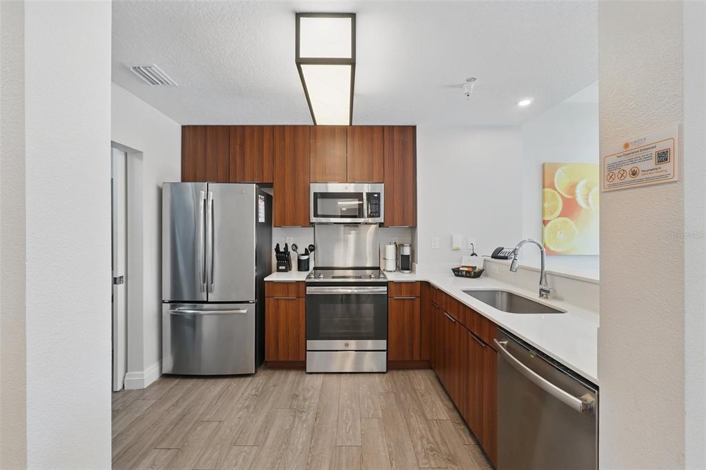 A modern kitchen features stainless steel appliances, wood-toned cabinets, and white countertops — 14501 GROVE RESORT AVENUE UNIT 2232, WINTER GARDEN, FL