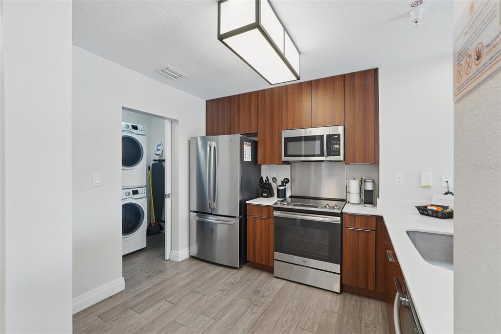 A modern kitchen features wood-toned cabinets, stainless steel appliances, and an adjacent laundry closet — 14501 GROVE RESORT AVENUE UNIT 2232, WINTER GARDEN, FL