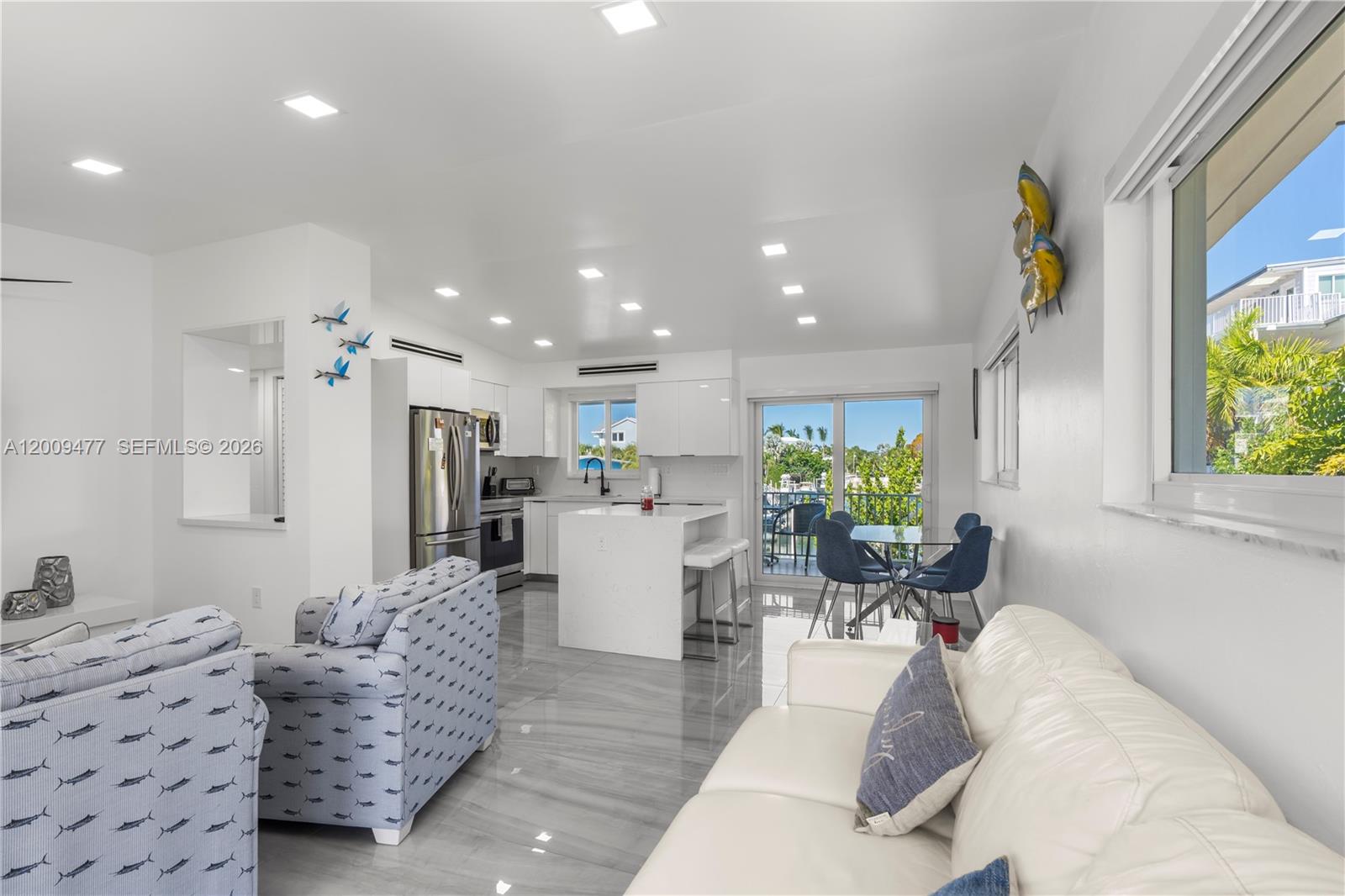 This open-concept living area features a modern kitchen, white cabinetry, and tile flooring — 200 Plantation Shores Dr, Tavernier FL 33070, TAVERNIER, FL