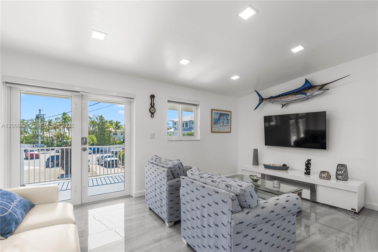 A living room features light gray tile floors, two patterned armchairs, and a mounted fish — 200 Plantation Shores Dr, Tavernier FL 33070, TAVERNIER, FL