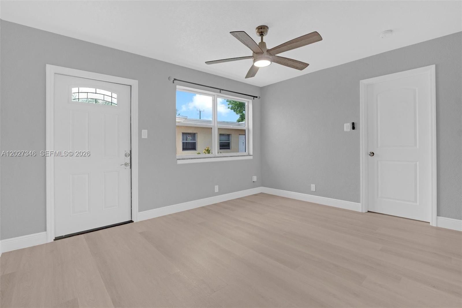 A room with light gray walls, wood-look flooring, a ceiling fan, and two white doors — 369 Phippen Waiters Rd # 1, Dania Beach FL 33004, DANIA BEACH, FL