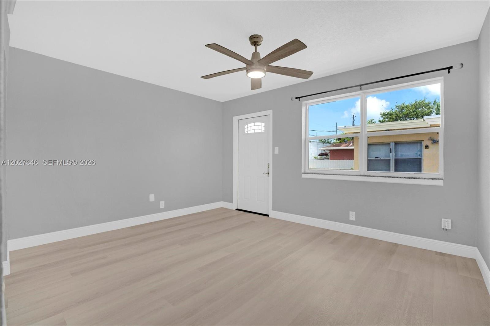 An empty room with light gray walls, wood-look flooring, a ceiling fan, and a window — 369 Phippen Waiters Rd # 1, Dania Beach FL 33004, DANIA BEACH, FL