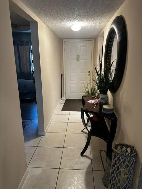 A tiled entryway features a console table, a round mirror, and a door — 3186 Via Poinciana # 306, FL 33467, FL