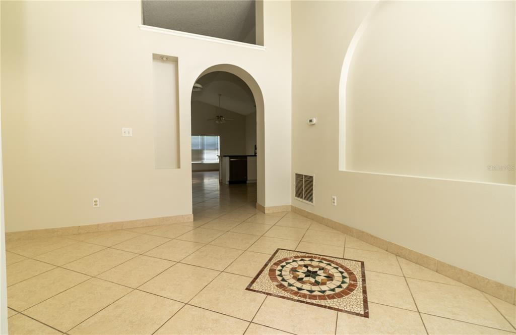 A tiled room features a decorative floor inlay, an arched doorway, and a recessed wall niche — 11547 GRAZELEY COURT, ORLANDO, FL