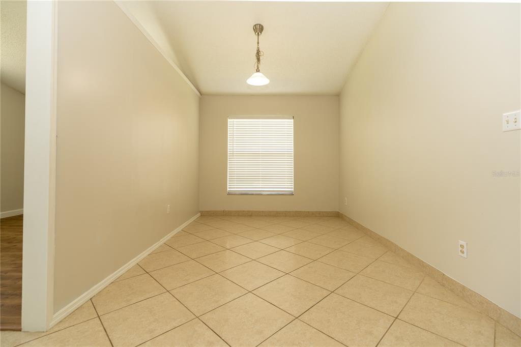 An empty dining area features beige walls, a single window with blinds, and tiled floors — 11547 GRAZELEY COURT, ORLANDO, FL