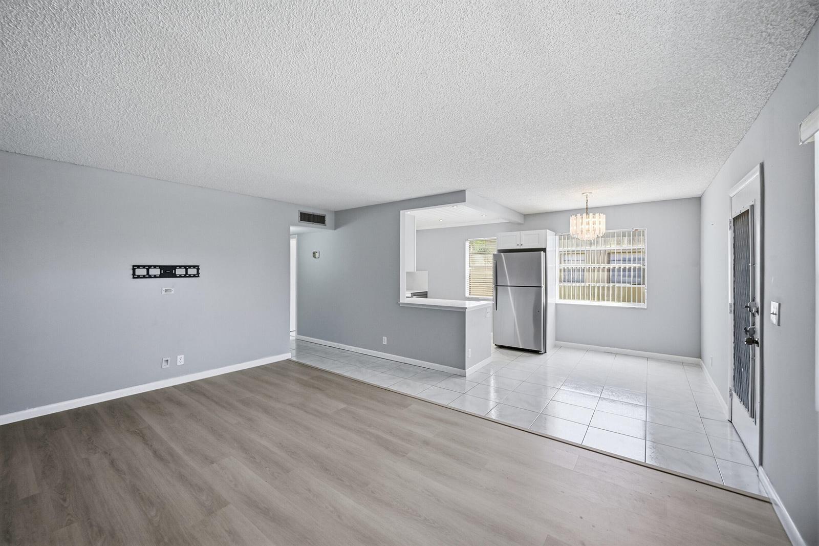 An open-concept living and dining area with light gray walls, wood-look flooring, and tile — 422 Burgundy I, Delray Beach FL 33484, DELRAY BEACH, FL