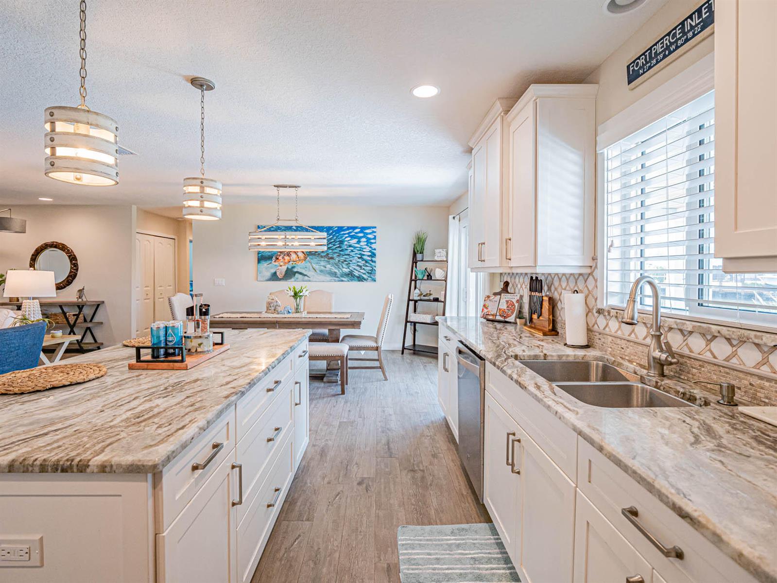 A kitchen with white cabinets, stone countertops, and a large island opens to a dining area — 255 Marina Drive, Fort Pierce FL 34949, FORT PIERCE, FL