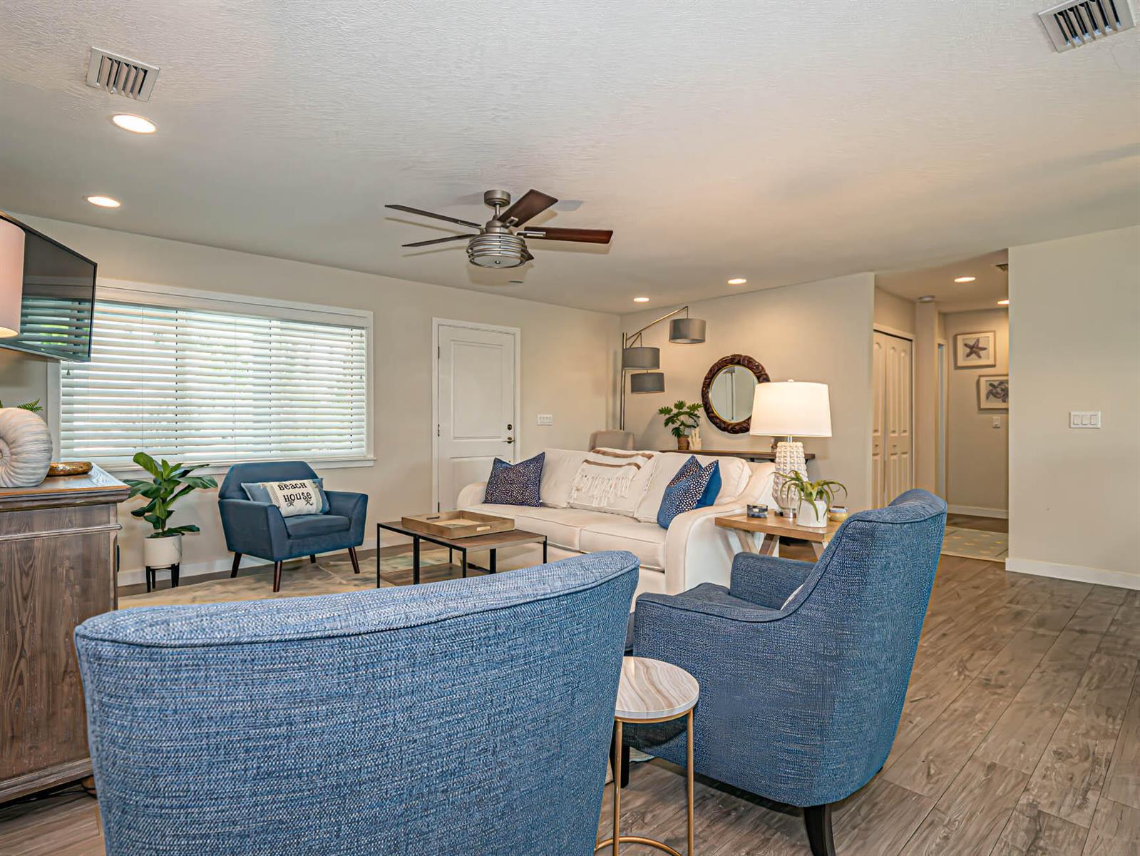 A living room features blue armchairs, a white sofa, and wood-look flooring — 255 Marina Drive, Fort Pierce FL 34949, FORT PIERCE, FL