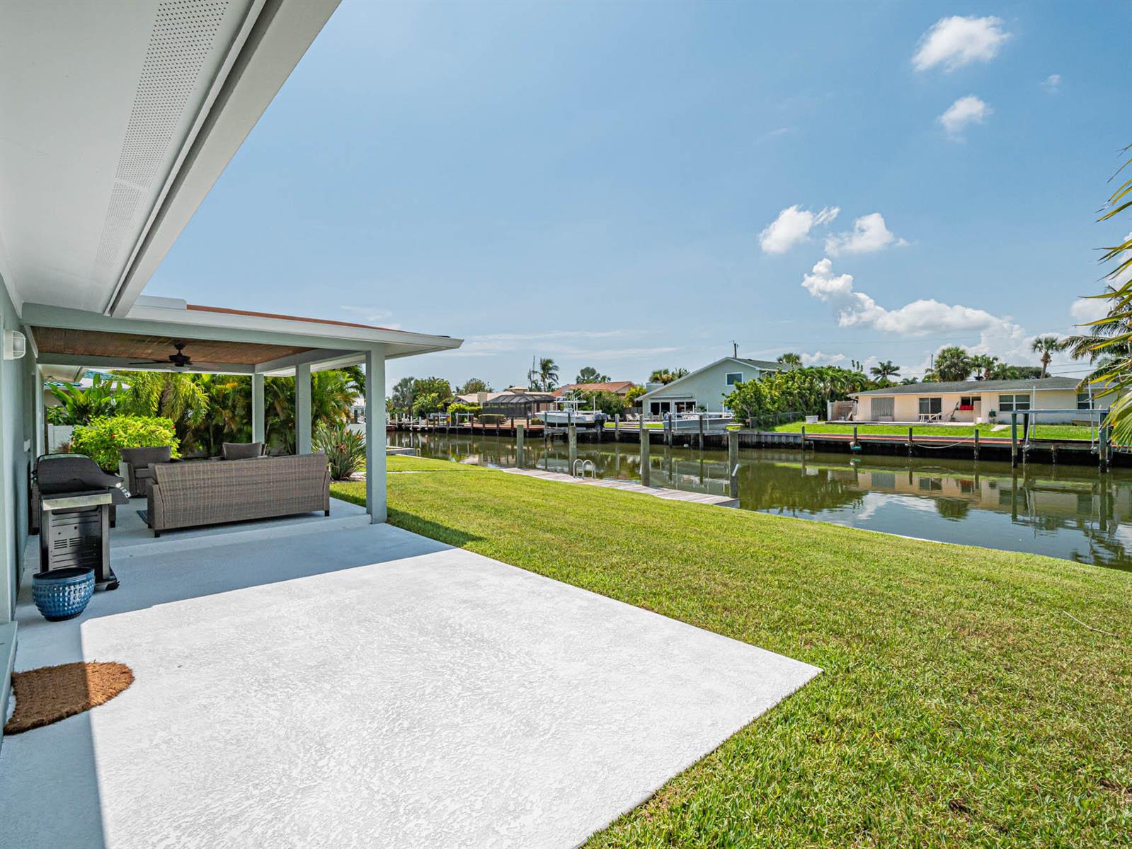 A covered patio overlooks a grassy backyard and a canal with boat docks — 255 Marina Drive, Fort Pierce FL 34949, FORT PIERCE, FL