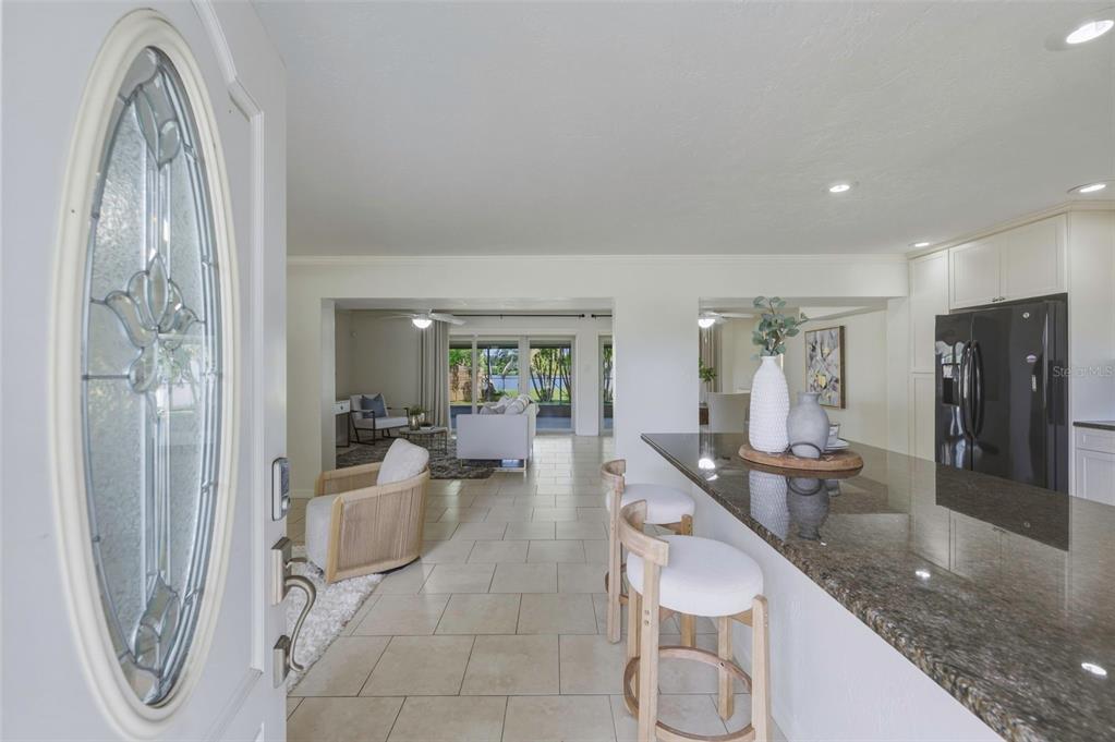 A view from an entryway into a kitchen with a granite island and living area — 7300 10TH STREET N, ST PETERSBURG, FL