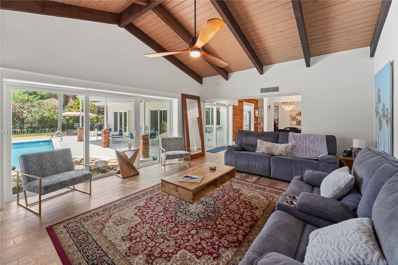 A living room features a vaulted wood-beam ceiling, a large area rug, and sliding glass doors — 8380 SW 186 St, Cutler Bay FL 33157, CUTLER BAY, FL