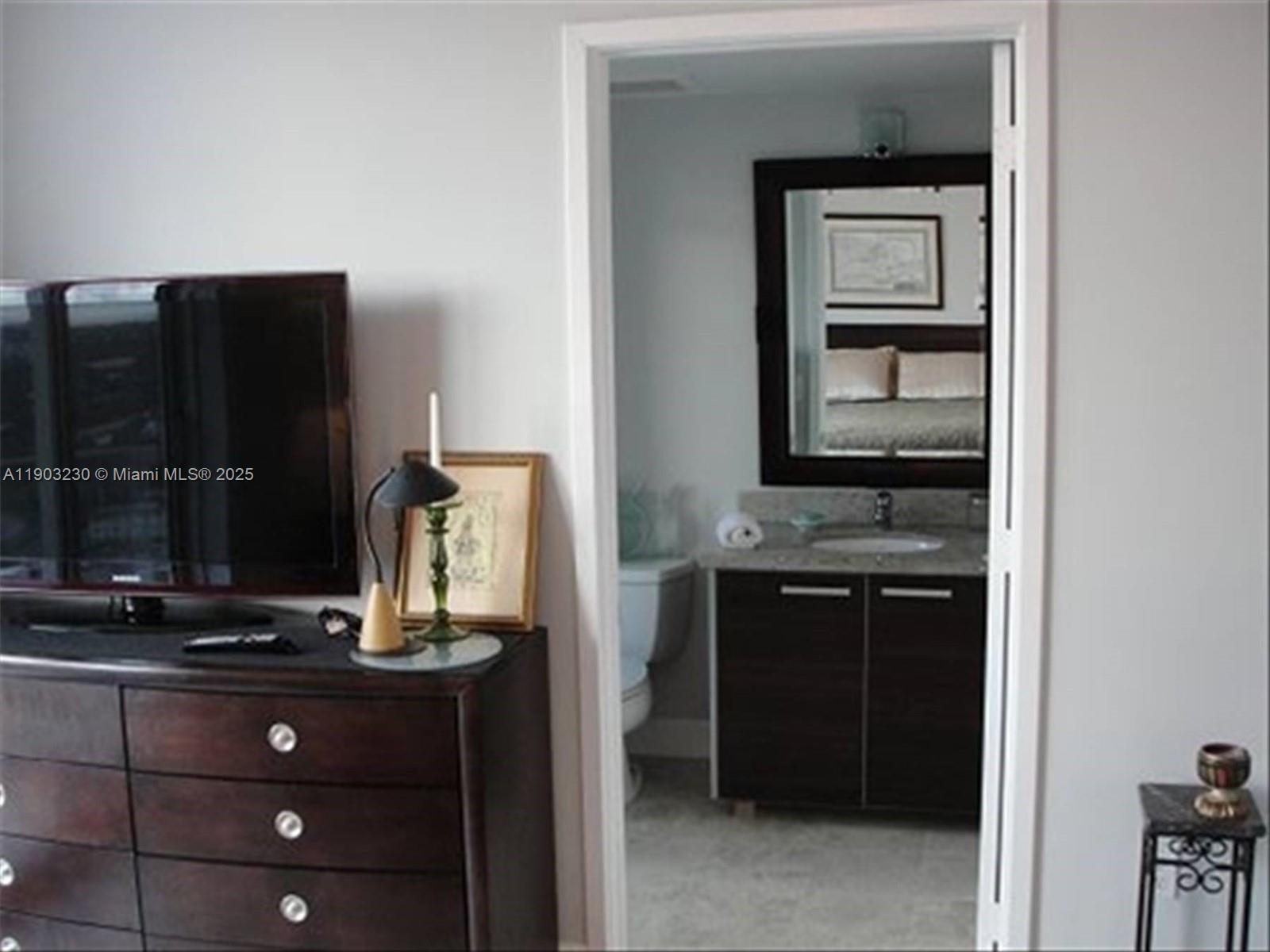 A bedroom dresser with a television sits beside a doorway leading into a bathroom — 185 SW 7 ST # 1802, Miami FL 33130, MIAMI, FL