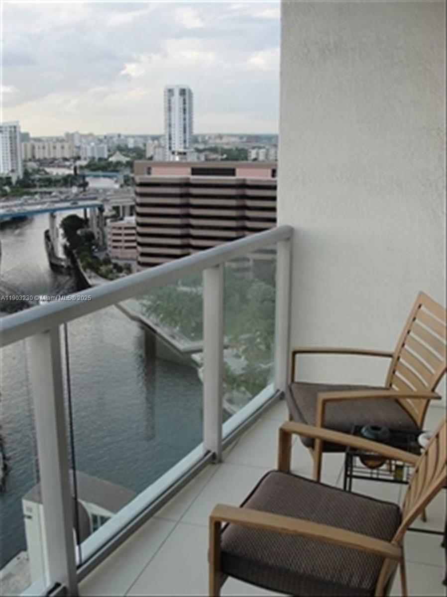A balcony with two chairs overlooks a river, a bridge, and city buildings — 185 SW 7 ST # 1802, Miami FL 33130, MIAMI, FL