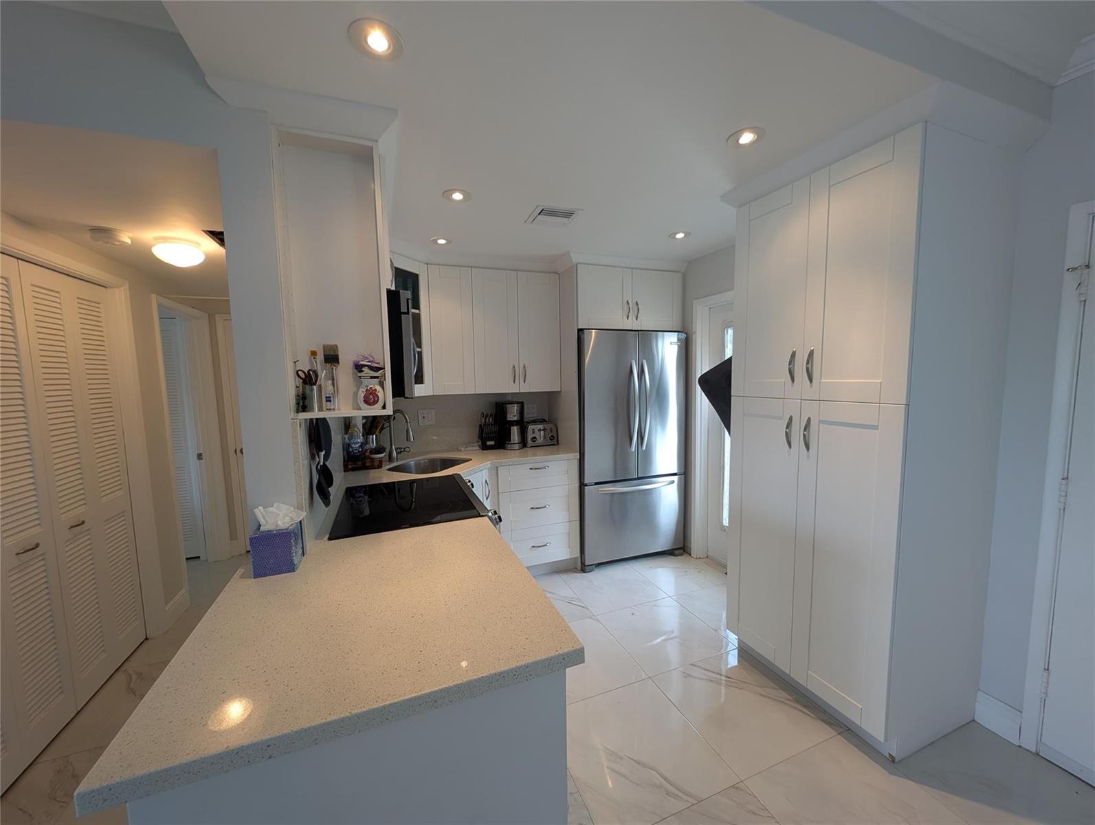 A kitchen with white cabinets, stainless steel appliances, and a light-colored quartz countertop — 3209 S Ocean Drive # 4E, Hallandale Beach FL 33009, HALLANDALE BEACH, FL