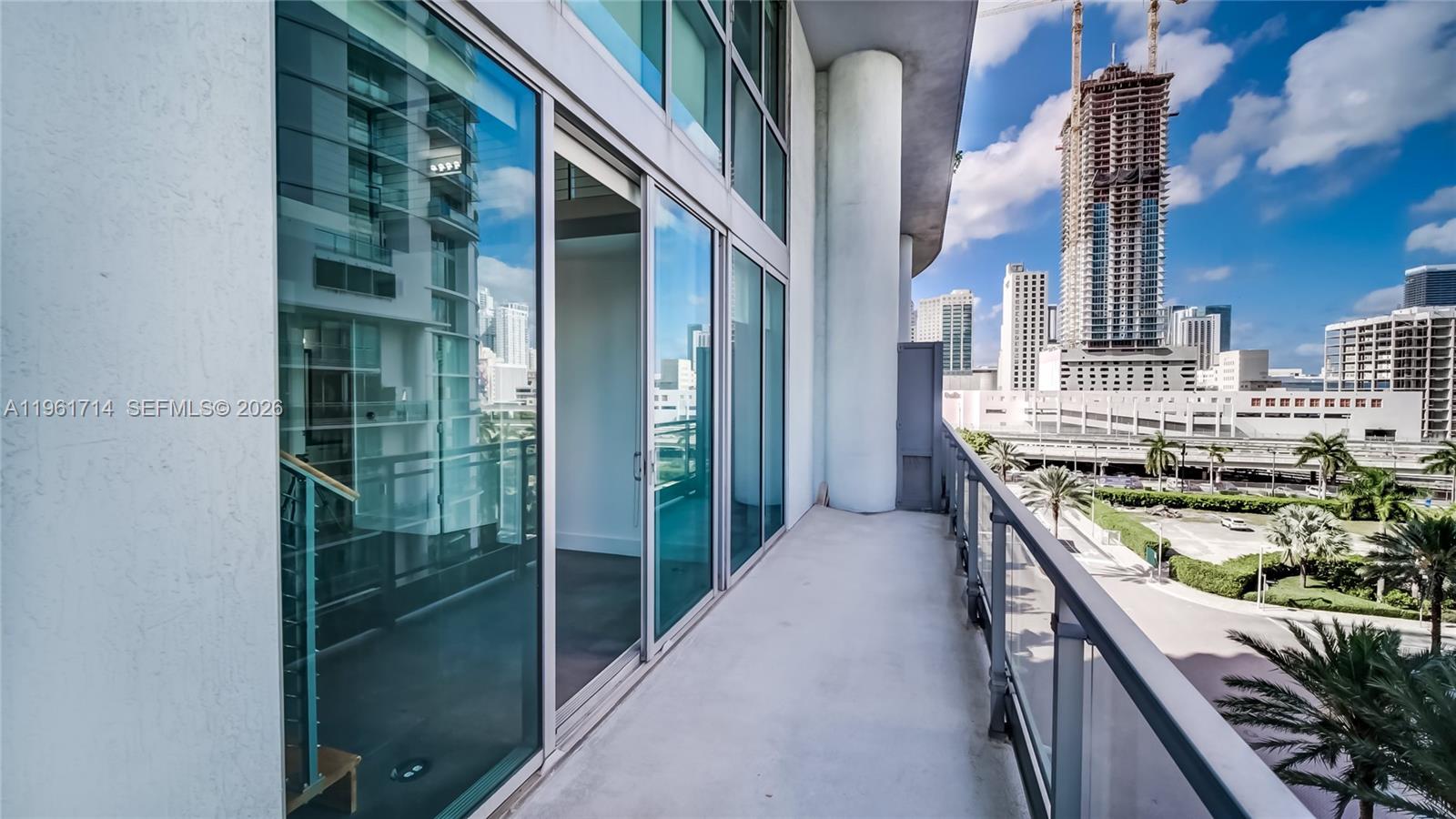 A balcony with glass railings overlooks a city skyline featuring high-rise buildings and construction — 90 SW 3rd St, Miami FL 33130, MIAMI, FL