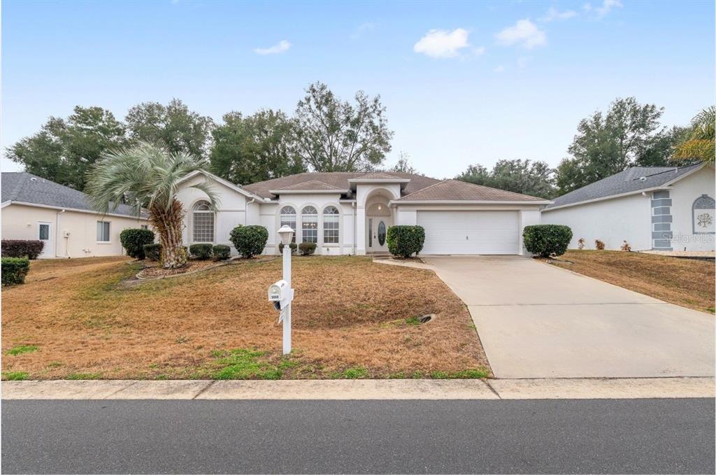 A single-story house with a white stucco exterior, a two-car garage, and a front lawn — 5888 NW 21ST STREET, OCALA, FL