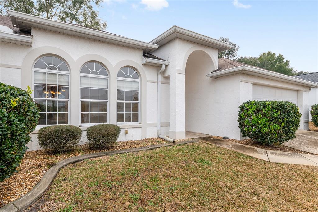 The exterior of a white stucco house features three arched windows and a covered entryway — 5888 NW 21ST STREET, OCALA, FL