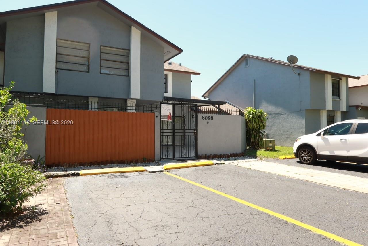 A two-story gray house features a fenced front courtyard and a paved parking area — 8098 NW 99th Ter, Hialeah Gardens FL 33016, HIALEAH GARDENS, FL