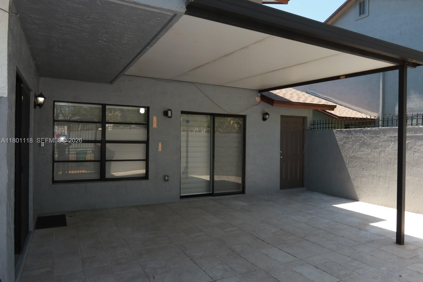 A covered patio area features tiled flooring, a sliding glass door, and a brown door — 8098 NW 99th Ter, Hialeah Gardens FL 33016, HIALEAH GARDENS, FL